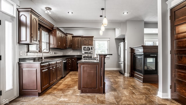 kitchen with sink, a kitchen island, dark brown cabinets, decorative light fixtures, and appliances with stainless steel finishes