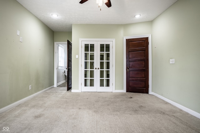 spare room featuring light carpet, ceiling fan, french doors, and a textured ceiling