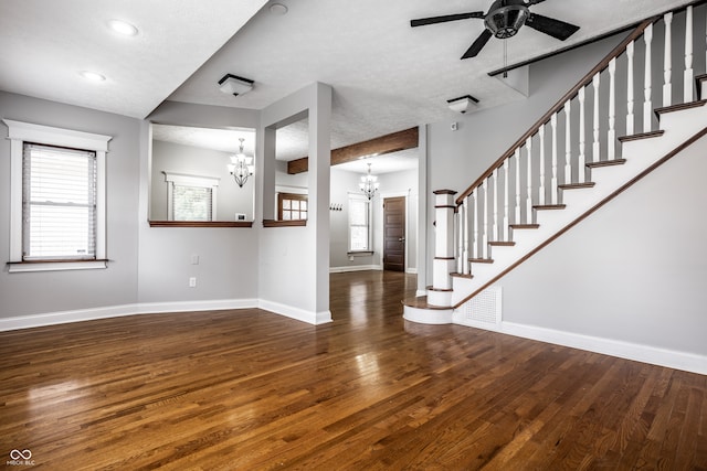 interior space featuring ceiling fan with notable chandelier, dark hardwood / wood-style floors, and a textured ceiling