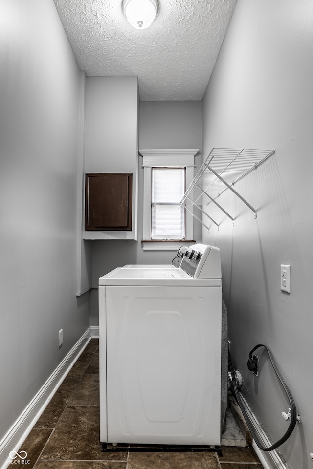 clothes washing area with washing machine and dryer and a textured ceiling