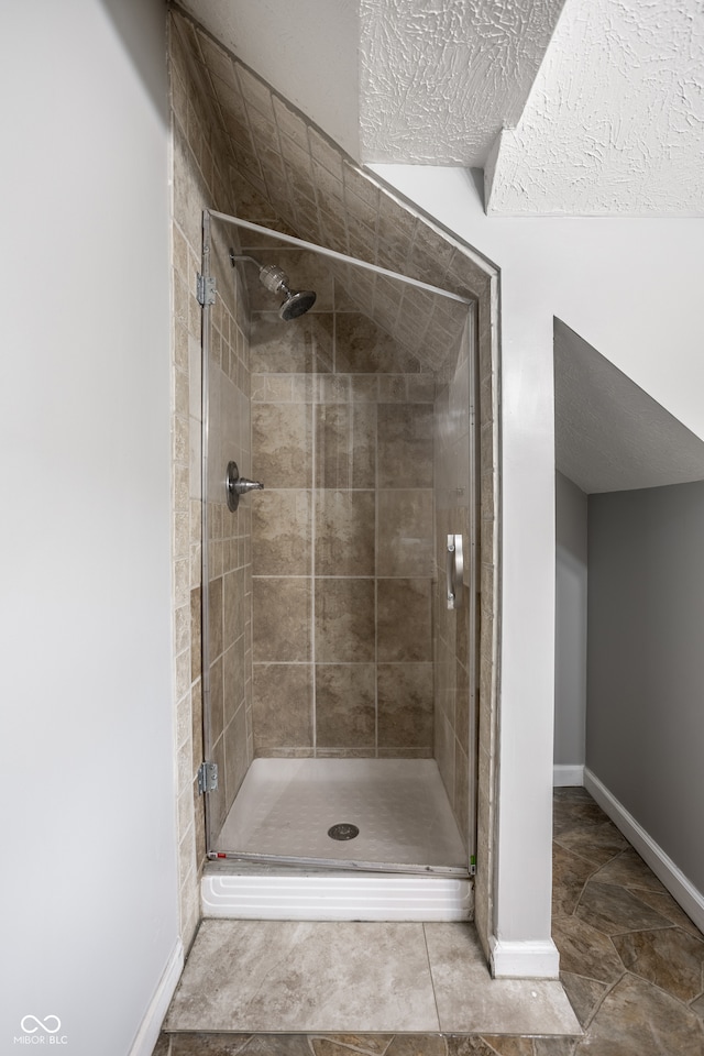 bathroom with tile patterned flooring, a shower with door, and a textured ceiling