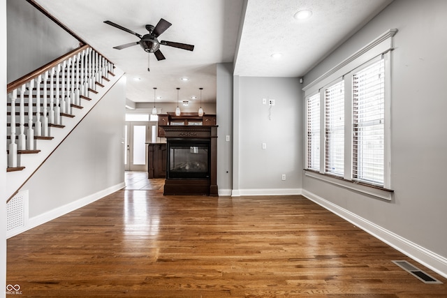 unfurnished living room featuring ceiling fan, dark wood-type flooring, and a textured ceiling