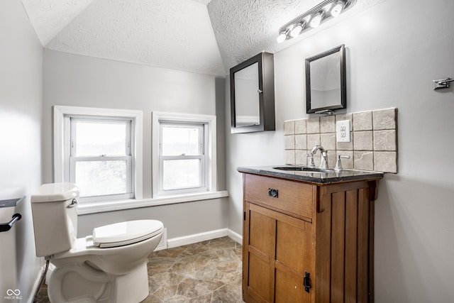 bathroom featuring toilet, tasteful backsplash, lofted ceiling, vanity, and a textured ceiling