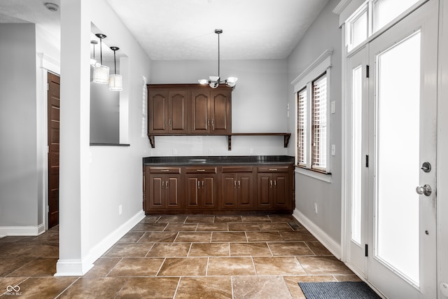 kitchen with dark brown cabinetry, an inviting chandelier, and decorative light fixtures