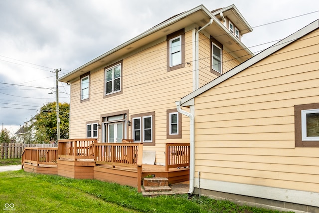 rear view of house featuring a wooden deck and a lawn