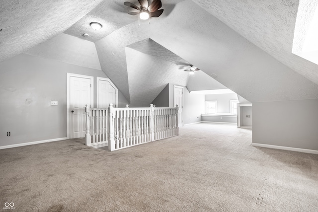 additional living space with ceiling fan, a textured ceiling, vaulted ceiling, and carpet