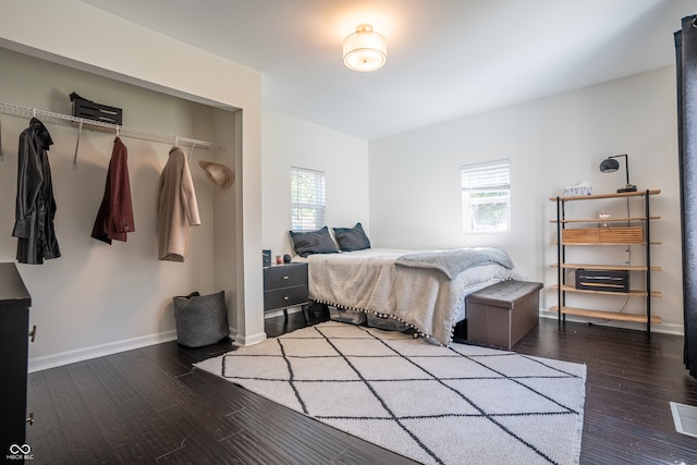 bedroom with multiple windows, a closet, and dark hardwood / wood-style flooring