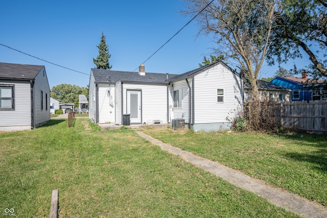 rear view of property featuring a lawn and central AC