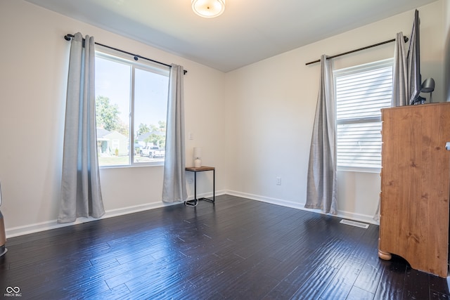 spare room with dark wood-type flooring and plenty of natural light