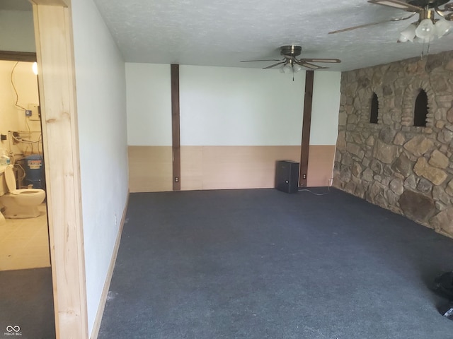 basement featuring dark carpet, a textured ceiling, and ceiling fan