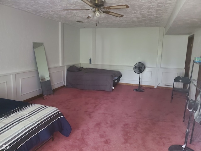 carpeted bedroom with ceiling fan and a textured ceiling