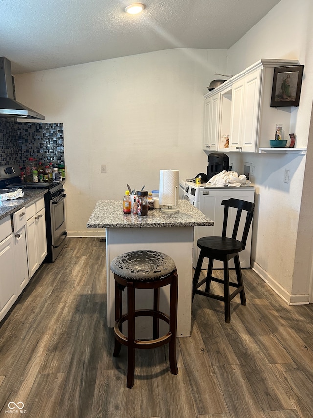 kitchen featuring a kitchen bar, wall chimney range hood, stainless steel range oven, and dark hardwood / wood-style floors