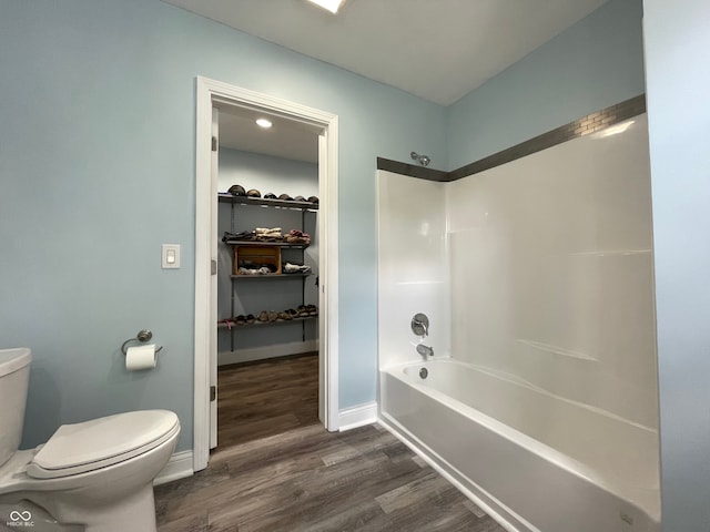 bathroom with wood-type flooring, bathing tub / shower combination, and toilet