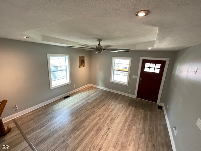 foyer featuring ceiling fan, a tray ceiling, hardwood / wood-style floors, and a textured ceiling