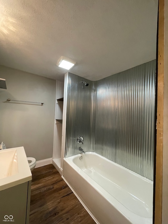 full bathroom featuring vanity, a textured ceiling, hardwood / wood-style flooring, washtub / shower combination, and toilet