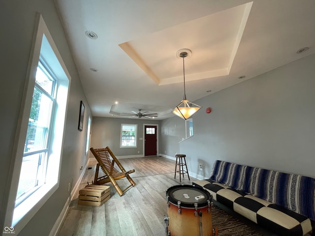 living room featuring ceiling fan, a tray ceiling, and hardwood / wood-style floors