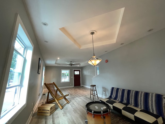 living room with ceiling fan, light hardwood / wood-style floors, and a raised ceiling