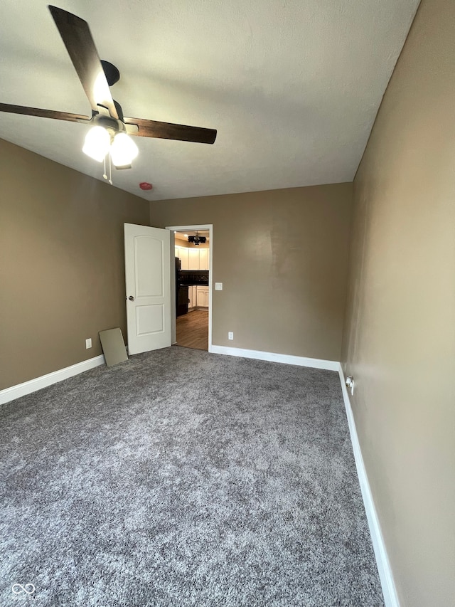 unfurnished bedroom featuring dark colored carpet, a textured ceiling, and ceiling fan