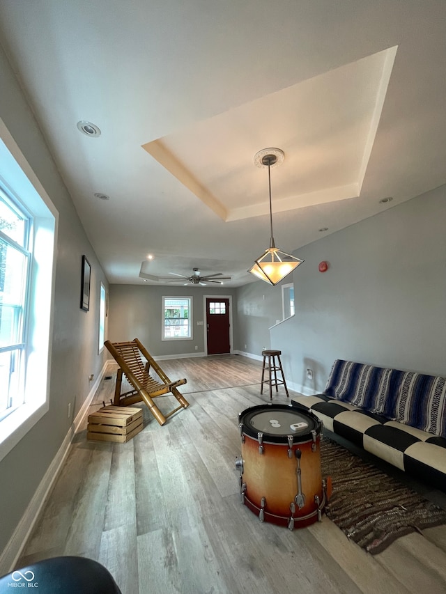 living room with ceiling fan, a tray ceiling, and light hardwood / wood-style floors