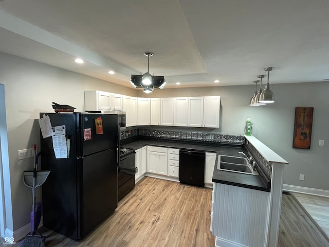 kitchen with black appliances, white cabinets, sink, light hardwood / wood-style floors, and hanging light fixtures