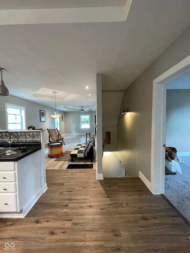 interior space featuring ceiling fan, hardwood / wood-style floors, decorative light fixtures, lofted ceiling, and white cabinets