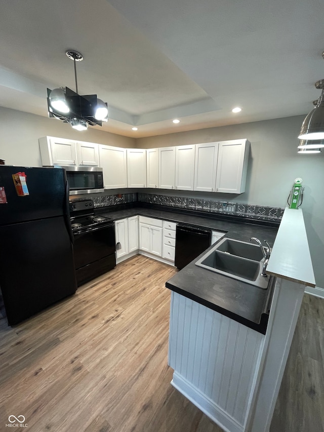 kitchen with black appliances, white cabinets, sink, light hardwood / wood-style flooring, and decorative light fixtures