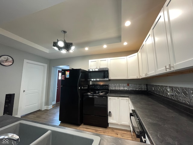 kitchen featuring light wood-type flooring, black appliances, and white cabinetry