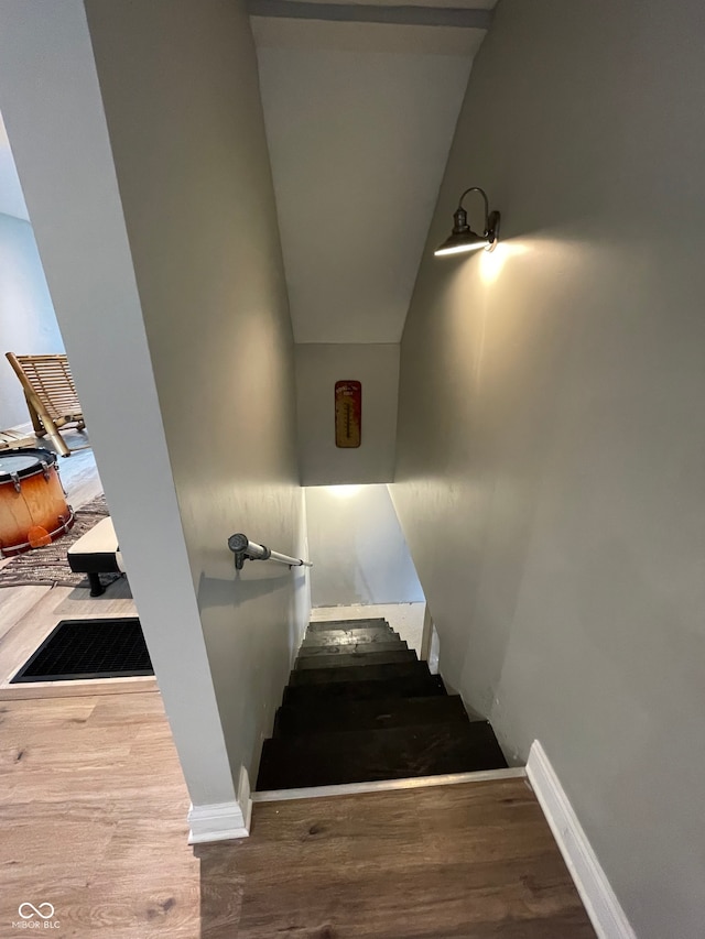 stairs with vaulted ceiling and wood-type flooring