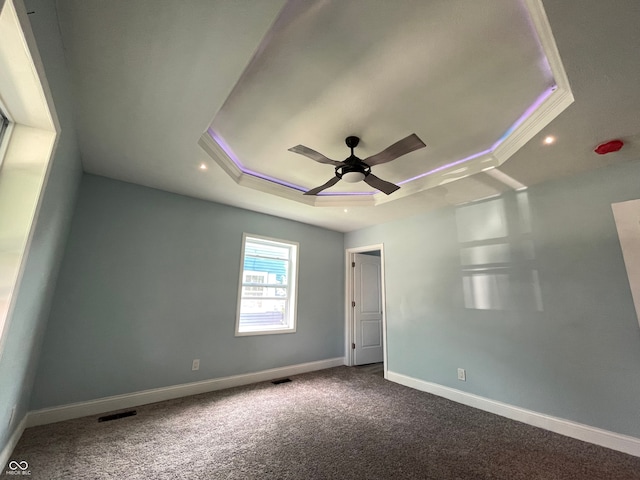 unfurnished room with carpet floors, crown molding, a tray ceiling, and ceiling fan