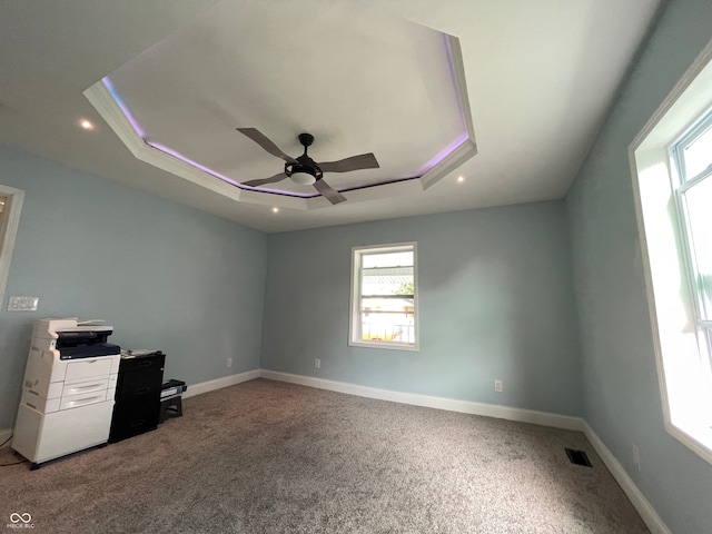 interior space with ceiling fan and a raised ceiling