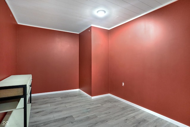 empty room with crown molding and light wood-type flooring