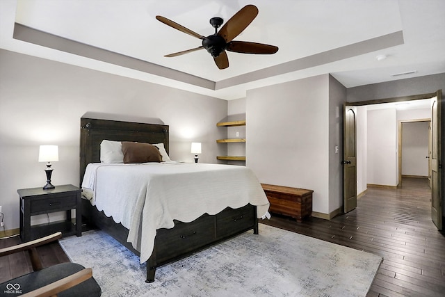 bedroom with ceiling fan, a raised ceiling, and wood-type flooring