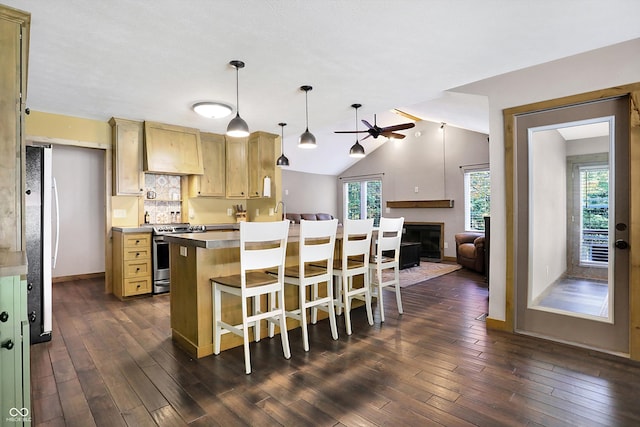 kitchen featuring lofted ceiling, hanging light fixtures, premium range hood, stainless steel range oven, and dark hardwood / wood-style flooring