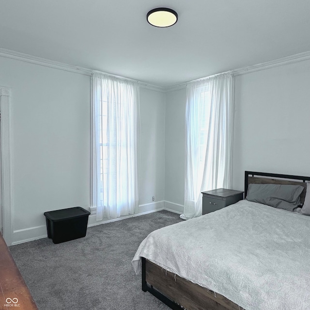 bedroom with ornamental molding and dark carpet