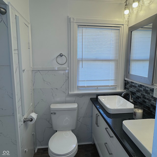 bathroom with vanity, toilet, and tile walls