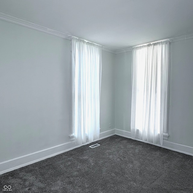 spare room featuring ornamental molding and dark carpet