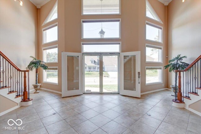 foyer entrance featuring baseboards, a towering ceiling, stairs, and plenty of natural light