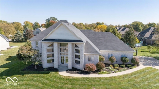 view of front facade featuring a shingled roof and a front yard