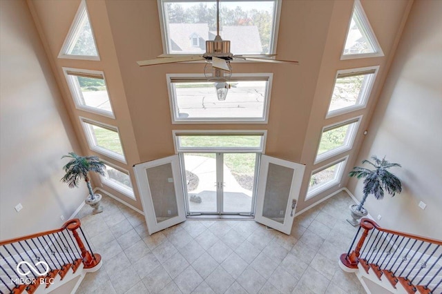 entryway featuring a healthy amount of sunlight, a towering ceiling, baseboards, and light tile patterned floors