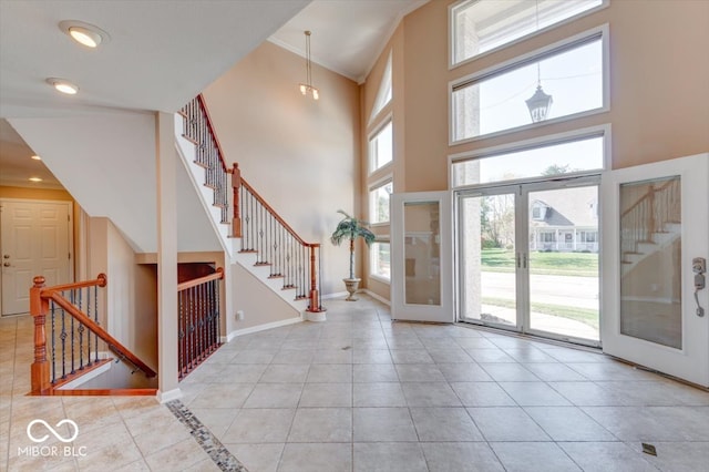 entryway featuring a towering ceiling, baseboards, tile patterned flooring, and stairs