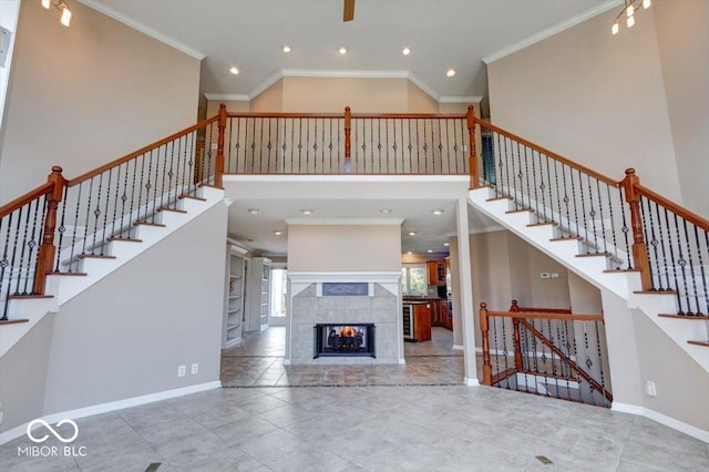 unfurnished living room with recessed lighting, a high ceiling, ornamental molding, baseboards, and a tiled fireplace