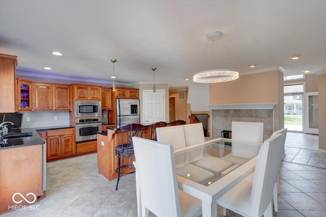 tiled dining area with sink, a tiled fireplace, an inviting chandelier, and ornamental molding