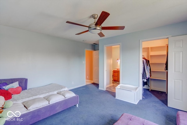 carpeted bedroom with ensuite bathroom, baseboards, a closet, ceiling fan, and a walk in closet