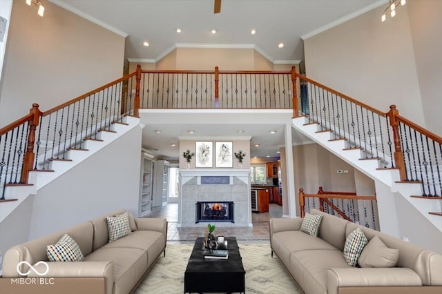 living room with a fireplace, a towering ceiling, and crown molding