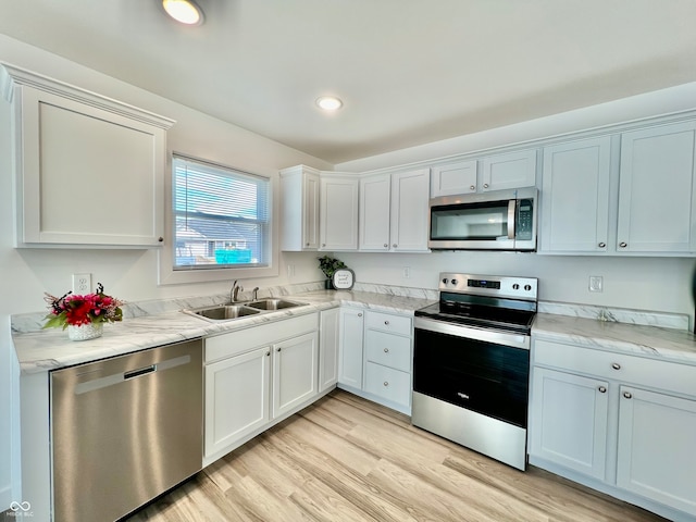 kitchen featuring sink, white cabinets, stainless steel appliances, and light hardwood / wood-style flooring