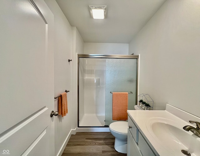 bathroom with vanity, toilet, wood-type flooring, and a shower with door