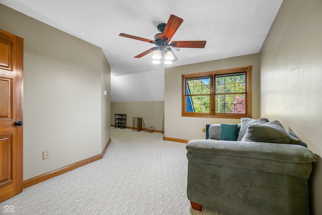 living area featuring a textured ceiling, light colored carpet, vaulted ceiling, and ceiling fan