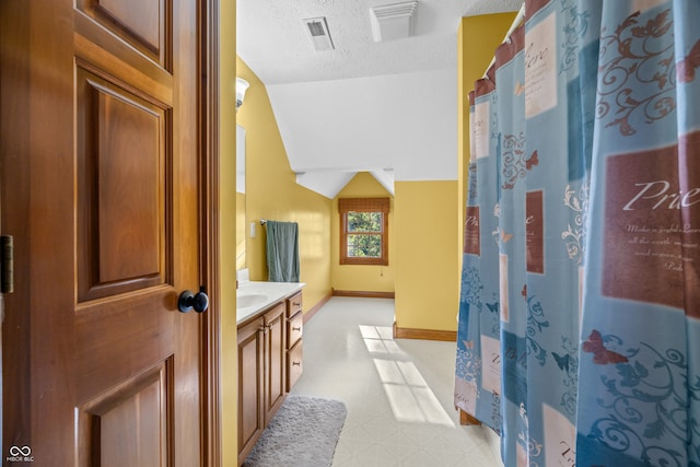 bathroom with vanity, vaulted ceiling, and a textured ceiling