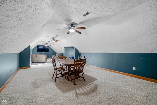 carpeted dining area featuring lofted ceiling, a textured ceiling, and ceiling fan