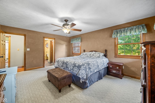 bedroom with ceiling fan, carpet flooring, a textured ceiling, and ensuite bathroom